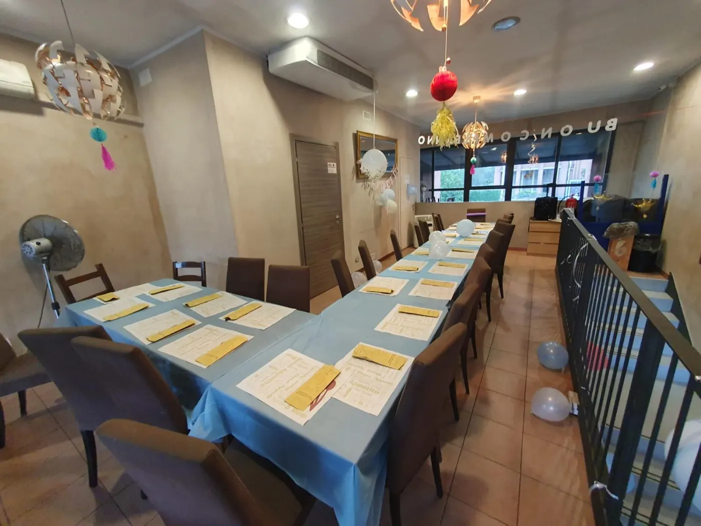 Il piano di sopra apparecchiato per un compleanno, con palloncini e un tavolone lungo